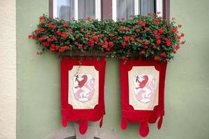 Rothenburg, Germany, 2014. Red geraniums and flags on a house in Rothenburg photo