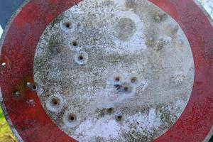 Detailed close up of bullet holes from gun shots in a traffic sign photo