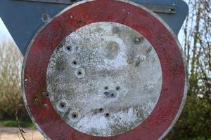 Detailed close up of bullet holes from gun shots in a traffic sign photo