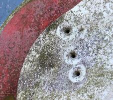 Detailed close up of bullet holes from gun shots in a traffic sign photo