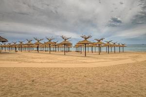 sombrillas de madera de belleza en una fila de playa de arena vacía foto