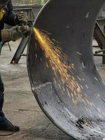 Fly bright sparks from the angle grinder machine. A young male welder in gloves grinds a metal product with angle grinder photo