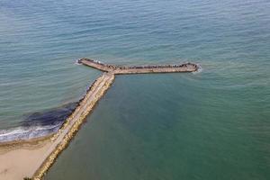 Aerial view from drone of the sea, beach and wave breaker stones photo