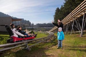 Sweden, 2022 - Happy family driving on alpine coaster photo