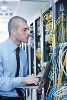 businessman with laptop in network server room photo