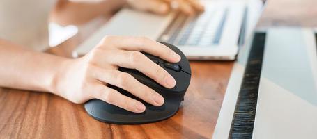 mano de mujer usando un mouse ergonómico de computadora, prevención del dolor de muñeca porque trabaja mucho tiempo. tenosinovitis de de quervain, síntoma de intersección, síndrome del túnel carpiano o concepto de síndrome de oficina foto