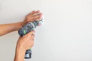 Electrician hand with cordless screwdriver installing Wire cables for socket plug to a concrete. Renovation, Repair, service and development of home and apartment concepts photo