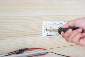 Man hand using screwdriver installing Wire cables for socket plug. Renovation, Repair, fixing and development of home and apartment concepts photo