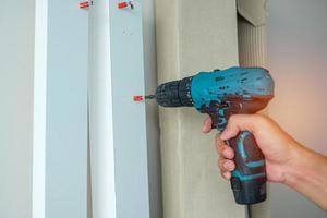 man using a cordless screwdriver assembling furniture at home, Carpenter working with electric screwdriver on the work photo