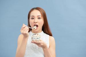 hermosa joven comiendo yogur fresco, pasas y avena para el desayuno. foto