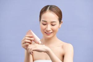 Smiling young woman applies cream on her hands. On a violetbackground. photo