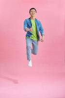 Handsome man jumping over pink photo
