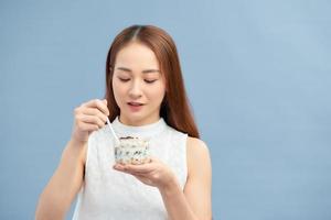 alimentos saludables para bajar de peso. mujer joven comiendo yogur, pasas y avena foto