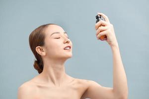 Beautiful asian woman holding spray water bottle isolated white background. photo