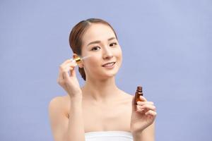 girl applying eye serum isolated on violet photo