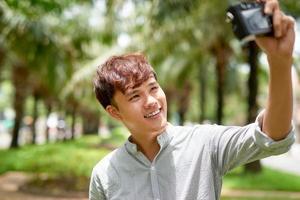 Portrait of a handsome young man taking a selfie with vintage camera photo