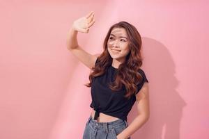 Close-up portrait of cheerful woman looking at camera, isolated on pink background photo