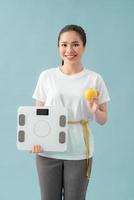 diet and fitness concept - beautiful sporty woman with scale, yellow apple and measuring tape photo