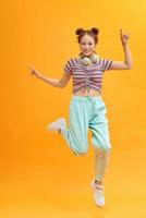 Full length photo of joyful lady jumping high listening modern youngster playlist music through cool earflaps isolated on yellow background