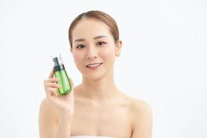 Happy young beautiful woman showing cosmetic bottle over white background. photo