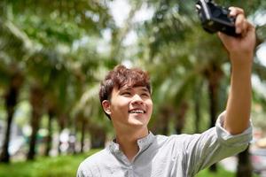 Happy Young Man take a Selfie with a Vintage Camera in the park outdoor photo