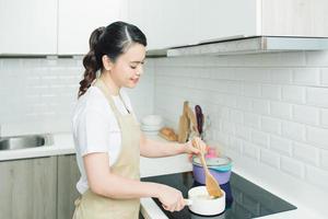 Cooking woman in kitchen with wooden spoon photo