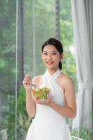 Portrait of happy young woman eating vegetables salad photo