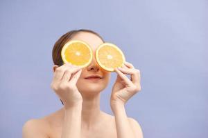 Pretty charming joyful attractive cheerful funny comic positive nude natural pure girl having two pieces of orange, closing one eye photo
