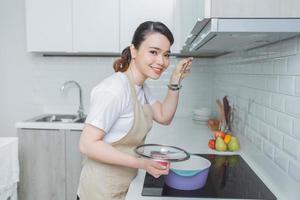 Portrait of beautiful young woman cooking soup with vegetables at home. photo