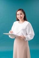 Portrait of smiling business woman with pen and paper folder. Young pretty worker writing something in her papers photo