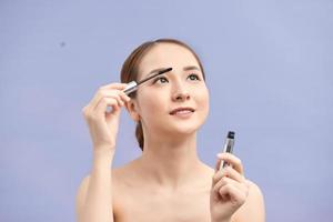 Girl makes makeup. Beautiful woman apply mascara on eyelashes with cosmetic brush photo