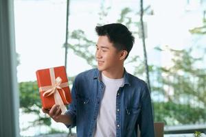 With love for you. Good looking young man in blue jeans shirt holding a gift box photo