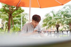 exitoso hipster esperando a un amigo en una cafetería mientras revisa fotos en una cámara antigua durante el tiempo libre