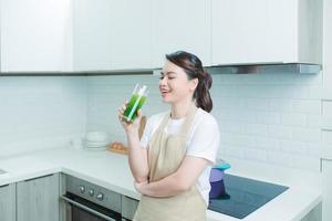 Happy smiling asian girl with glass of healthy fresh raw vegetable smoothie at home. photo
