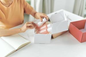 Cropped image of woman hands packing shipment with set skincare products in box for delivery photo