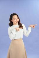 Attractive brunette girl isolated over purple background pointing at a copy space photo