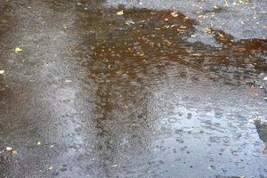 Rain water drops falling to the city street floor in autumn rainy day photo