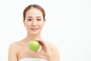 modelo bonito sonriente sosteniendo manzana mientras posa sobre fondo blanco foto