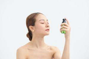 Beautiful asian woman applying spray water on face isolated white background. photo