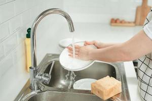 Woman washing plate in modern kitchen, closeup photo