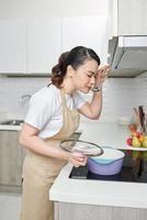 mujer joven de pie junto a la estufa en la cocina foto