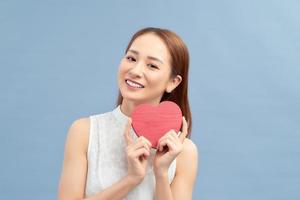 Love and valentines day woman holding heart smiling cute and adorable isolated on blue background. photo