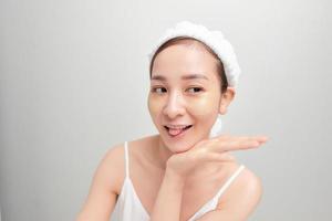 primer plano de una hermosa joven asiática con toalla de baño en la cabeza cubriendo su cabeza sobre fondo blanco. foto