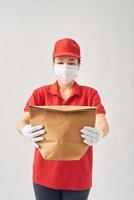 Young asian woman holding delivery paper bag for takeaway food over pink isolated background photo