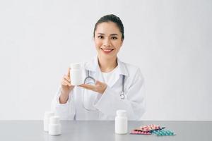 médico asiático que busca una cápsula de vitamina o medicina en una pequeña botella de vidrio, para mostrar al paciente y la medicina recetada antes de explicar cómo comer foto