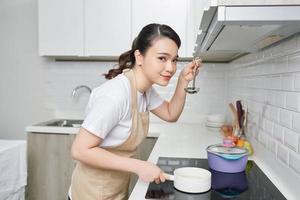 young woman is tasting her cooking in the kitchen photo