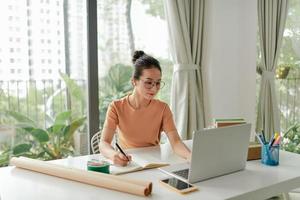 A young woman starting an online business works on her laptop and waits for orders photo