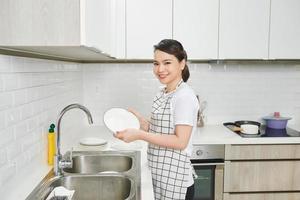 mujer lavando los platos en la cocina foto