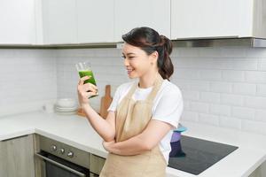 Detox Concept. Close up portrait of asian girl holding glass with homemade green juice, looking aside at free space photo