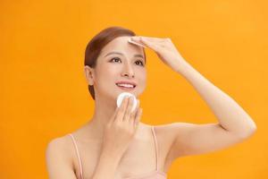 Woman using cotton pad. Happy smiling beautiful young woman cleaning skin by cotton pad. photo